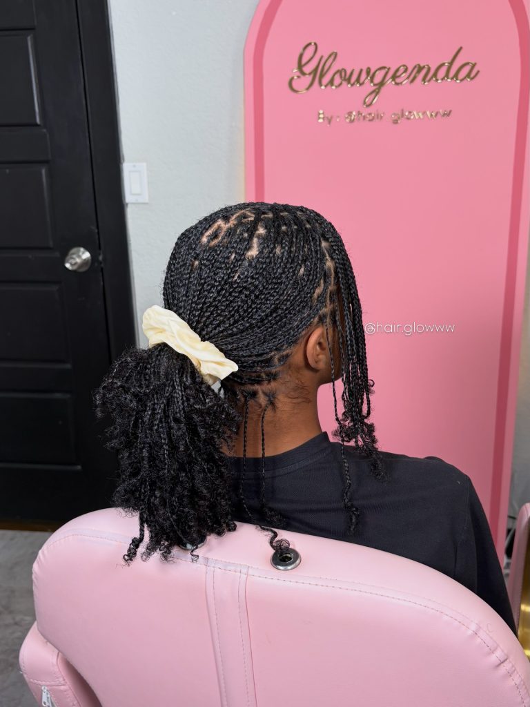 mini braids on natural hair with curly ends styled in a low messy pony with bangs