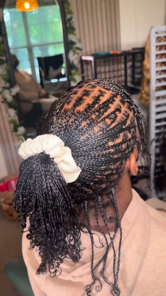 natural hair mini braids with curly ends in a messy ponytail