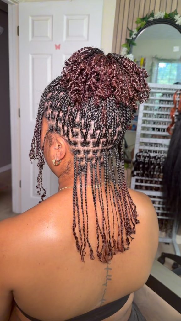 Natural hair mini braids with curly ends styled in a high messy ponytail