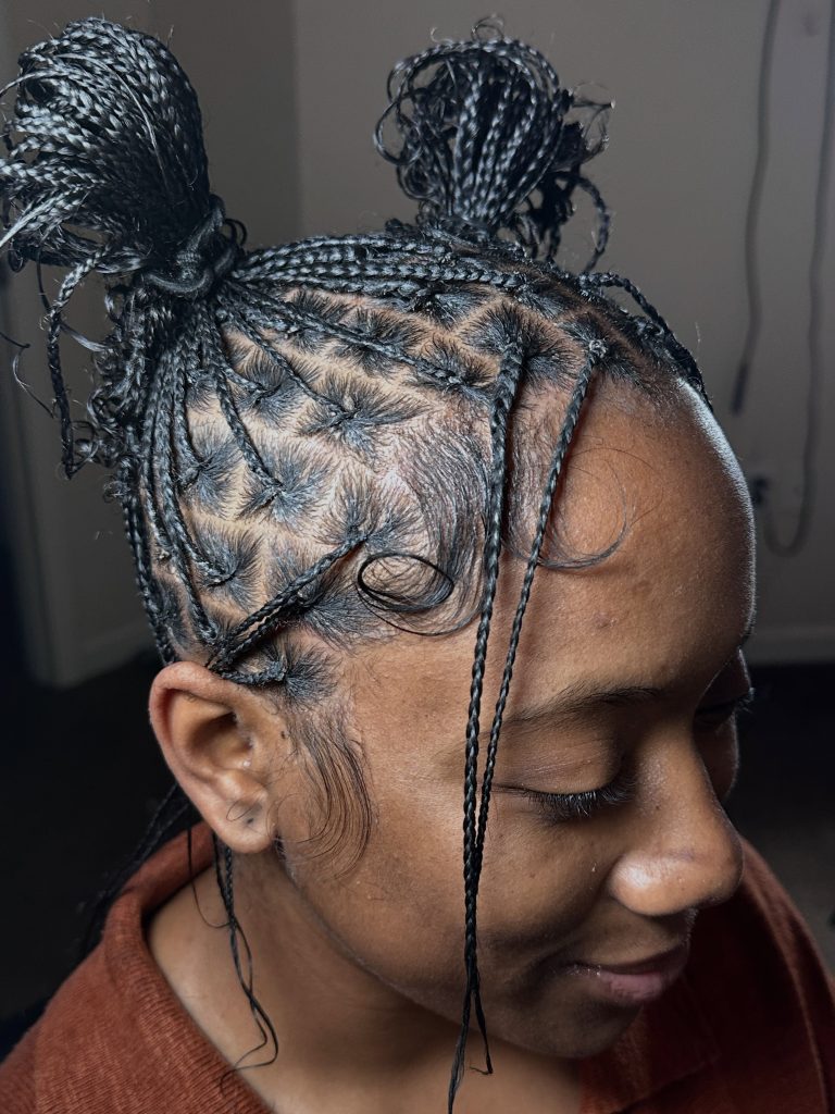 Natural hair mini braids with curly ends styled in two messy buns