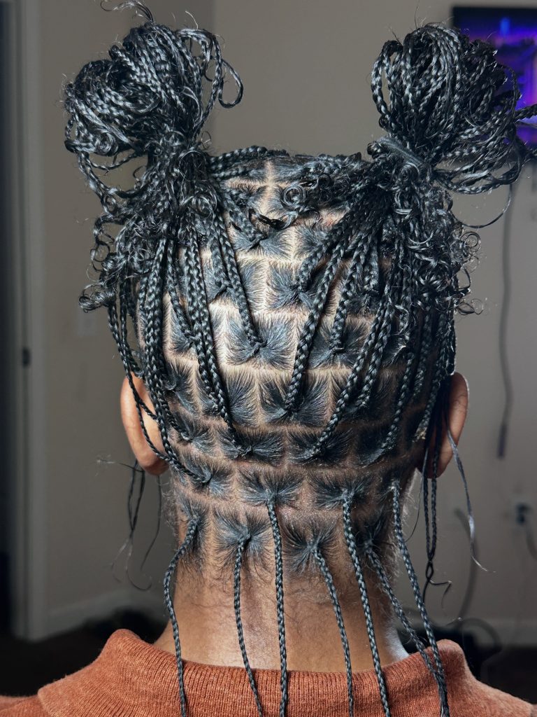 Natural hair mini braids with curly ends styled in two messy buns